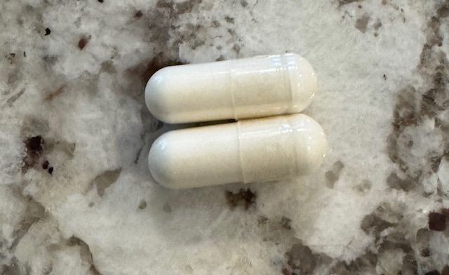 This photo shows two magnesium gel caps placed on a marble countertop.