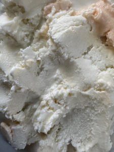 This photo shows vanilla and orange cream ice cream flattened onto a surface. The picture is taken up close to reveal the frost and ridges from the spoon used to flatten it out onto the surface.
