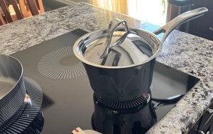 This photo shows a black stovetop with a bell-shaped silver pan on top.