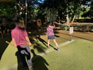 This photo shows Cecilia as she's throwing a spear, outdoors in a grassy area. The instructor stands next to her.