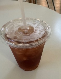 This image shows a plastic cup with a plastic lid and straw. Inside is a cola-colored liquid with ice.