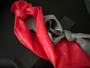 This is a photo of various resistance bands in red, black, and gray against a black background.