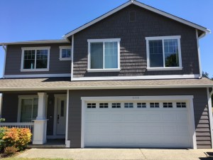 This is a photo of the outside of a house that's painted gray and white. It's a Craftsman-style house with a small front porch.