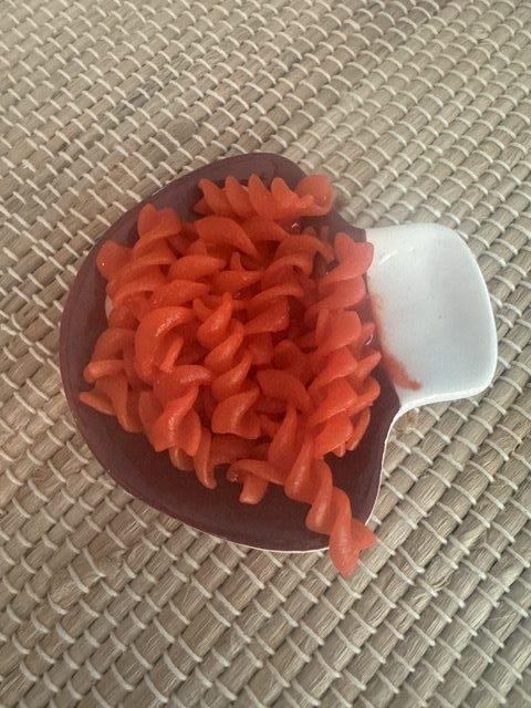 This is a photo of Flamin' Hot Cheetos Kraft Mac and Cheese spiral pasta on a mushroom shaped ceramic plate. The plate is placed on a bamboo-like table runner.